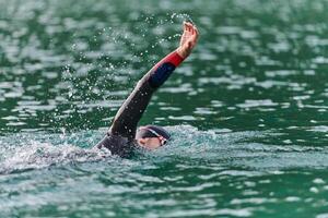 A professional triathlete trains with unwavering dedication for an upcoming competition at a lake, emanating a sense of athleticism and profound commitment to excellence. photo