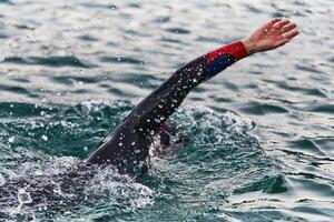A professional triathlete trains with unwavering dedication for an upcoming competition at a lake, emanating a sense of athleticism and profound commitment to excellence. photo