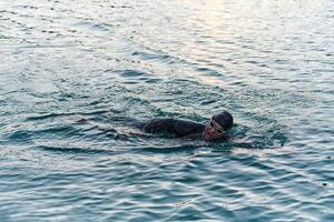 A professional triathlete trains with unwavering dedication for an upcoming competition at a lake, emanating a sense of athleticism and profound commitment to excellence. photo