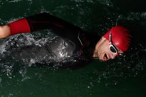 A determined professional triathlete undergoes rigorous night time training in cold waters, showcasing dedication and resilience in preparation for an upcoming triathlon swim competition photo