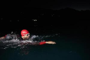 A determined professional triathlete undergoes rigorous night time training in cold waters, showcasing dedication and resilience in preparation for an upcoming triathlon swim competition photo