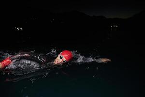 A determined professional triathlete undergoes rigorous night time training in cold waters, showcasing dedication and resilience in preparation for an upcoming triathlon swim competition photo