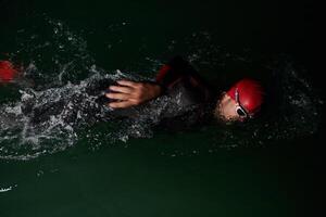 A determined professional triathlete undergoes rigorous night time training in cold waters, showcasing dedication and resilience in preparation for an upcoming triathlon swim competition photo