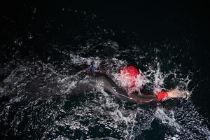 A determined professional triathlete undergoes rigorous night time training in cold waters, showcasing dedication and resilience in preparation for an upcoming triathlon swim competition photo