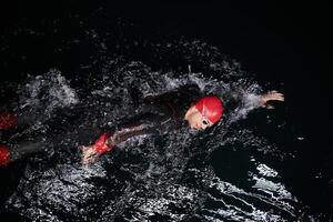 A determined professional triathlete undergoes rigorous night time training in cold waters, showcasing dedication and resilience in preparation for an upcoming triathlon swim competition photo