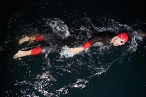 A determined professional triathlete undergoes rigorous night time training in cold waters, showcasing dedication and resilience in preparation for an upcoming triathlon swim competition photo