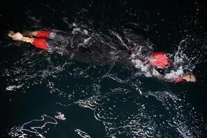 A determined professional triathlete undergoes rigorous night time training in cold waters, showcasing dedication and resilience in preparation for an upcoming triathlon swim competition photo