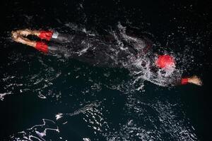 A determined professional triathlete undergoes rigorous night time training in cold waters, showcasing dedication and resilience in preparation for an upcoming triathlon swim competition photo