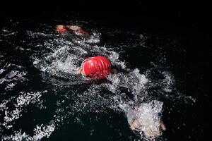 A determined professional triathlete undergoes rigorous night time training in cold waters, showcasing dedication and resilience in preparation for an upcoming triathlon swim competition photo