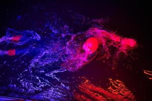 Authentic triathlete swimmer having a break during hard training on night neon gel light photo