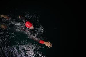 A determined professional triathlete undergoes rigorous night time training in cold waters, showcasing dedication and resilience in preparation for an upcoming triathlon swim competition photo