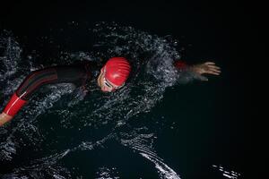 A determined professional triathlete undergoes rigorous night time training in cold waters, showcasing dedication and resilience in preparation for an upcoming triathlon swim competition photo