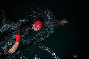 A determined professional triathlete undergoes rigorous night time training in cold waters, showcasing dedication and resilience in preparation for an upcoming triathlon swim competition photo