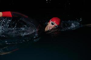 A determined professional triathlete undergoes rigorous night time training in cold waters, showcasing dedication and resilience in preparation for an upcoming triathlon swim competition photo