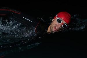 A determined professional triathlete undergoes rigorous night time training in cold waters, showcasing dedication and resilience in preparation for an upcoming triathlon swim competition photo