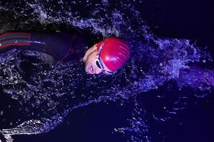 A determined professional triathlete undergoes rigorous night time training in cold waters, showcasing dedication and resilience in preparation for an upcoming triathlon swim competition photo