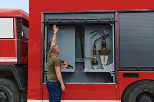A dedicated firefighter preparing a modern firetruck for deployment to hazardous fire-stricken areas, demonstrating readiness and commitment to emergency response photo