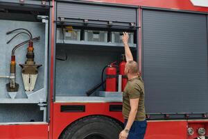 A dedicated firefighter preparing a modern firetruck for deployment to hazardous fire-stricken areas, demonstrating readiness and commitment to emergency response photo