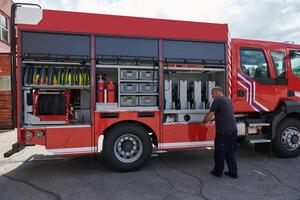 A dedicated firefighter preparing a modern firetruck for deployment to hazardous fire-stricken areas, demonstrating readiness and commitment to emergency response photo