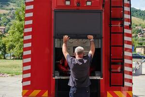 A dedicated firefighter preparing a modern firetruck for deployment to hazardous fire-stricken areas, demonstrating readiness and commitment to emergency response photo