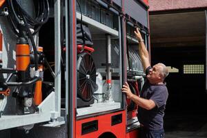A dedicated firefighter preparing a modern firetruck for deployment to hazardous fire-stricken areas, demonstrating readiness and commitment to emergency response photo