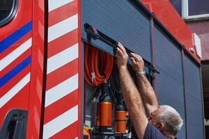 A dedicated firefighter preparing a modern firetruck for deployment to hazardous fire-stricken areas, demonstrating readiness and commitment to emergency response photo
