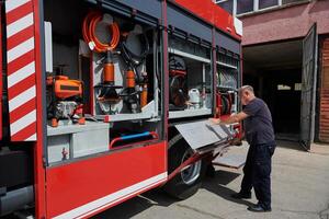 A dedicated firefighter preparing a modern firetruck for deployment to hazardous fire-stricken areas, demonstrating readiness and commitment to emergency response photo