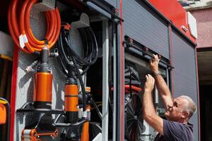 A dedicated firefighter preparing a modern firetruck for deployment to hazardous fire-stricken areas, demonstrating readiness and commitment to emergency response photo