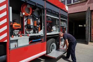 A dedicated firefighter preparing a modern firetruck for deployment to hazardous fire-stricken areas, demonstrating readiness and commitment to emergency response photo