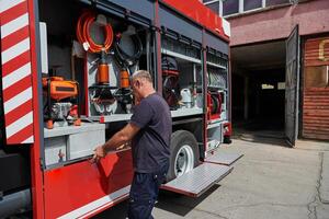 A dedicated firefighter preparing a modern firetruck for deployment to hazardous fire-stricken areas, demonstrating readiness and commitment to emergency response photo