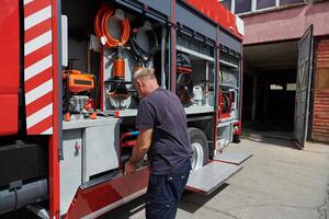 A dedicated firefighter preparing a modern firetruck for deployment to hazardous fire-stricken areas, demonstrating readiness and commitment to emergency response photo
