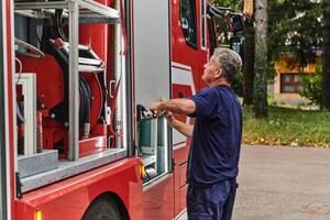A dedicated firefighter preparing a modern firetruck for deployment to hazardous fire-stricken areas, demonstrating readiness and commitment to emergency response photo