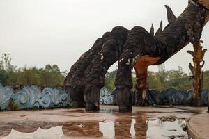 A weathered Chinese dragon statue in a deserted amusement park, covered in moss and rust. Abandoned Waterpark in Hue, Vietnam. photo