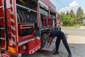 A dedicated firefighter preparing a modern firetruck for deployment to hazardous fire-stricken areas, demonstrating readiness and commitment to emergency response photo