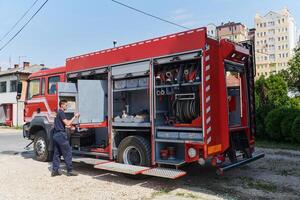 A dedicated firefighter preparing a modern firetruck for deployment to hazardous fire-stricken areas, demonstrating readiness and commitment to emergency response photo