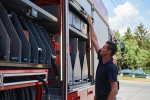 A dedicated firefighter preparing a modern firetruck for deployment to hazardous fire-stricken areas, demonstrating readiness and commitment to emergency response photo
