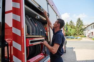 A dedicated firefighter preparing a modern firetruck for deployment to hazardous fire-stricken areas, demonstrating readiness and commitment to emergency response photo