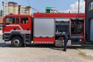 A dedicated firefighter preparing a modern firetruck for deployment to hazardous fire-stricken areas, demonstrating readiness and commitment to emergency response photo