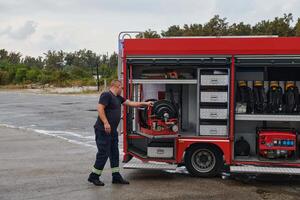 A dedicated firefighter preparing a modern firetruck for deployment to hazardous fire-stricken areas, demonstrating readiness and commitment to emergency response photo