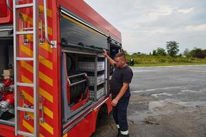 A dedicated firefighter preparing a modern firetruck for deployment to hazardous fire-stricken areas, demonstrating readiness and commitment to emergency response photo