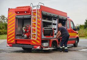 A dedicated firefighter preparing a modern firetruck for deployment to hazardous fire-stricken areas, demonstrating readiness and commitment to emergency response photo