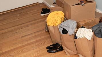Cardboard boxes with clothes, shoes on the floor things and stuff for moving, Relocation day moving concept. photo