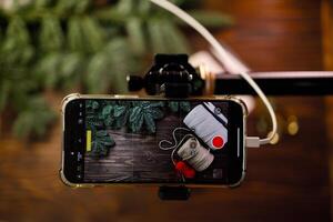 POV phone shooting photo or for vlog with craft supplies on wooden table decorated with spruce branches. Concept of filming tutorial for web vlog about handmade crafting. Xmas and winter leisure