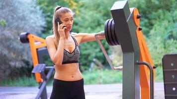 Woman using smartphone while putting weights on exercise machine video
