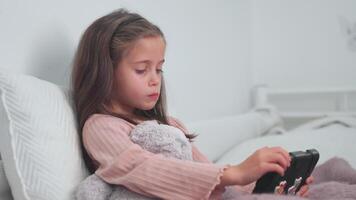 Sick girl using digital tablet while sitting with blanket in bed at home video