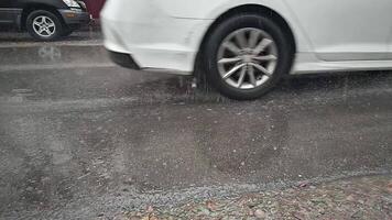 white car passing by on wet asphalt during rainfall with splashes video