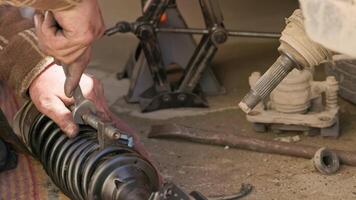 The calloused hands of a mechanic twist the coil spring ties with a wrench during DIY car repairs. video