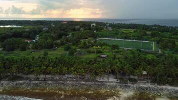 Fuvahmulah island in Maldives with local town at sunset with cloudy sky. Aerial view video