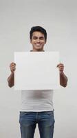 A smiling Indian man holds a white signboard in his hands photo