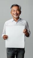 A mature man in Thailand smiling while holding a blank white sign photo